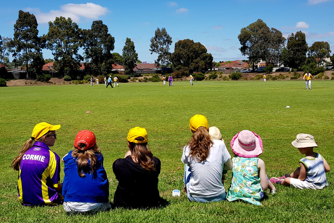 Image of children watching their mum's and family play cricket